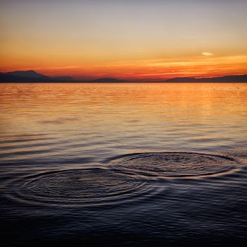 Ripples on the surface of water during sunset with hills in the distance