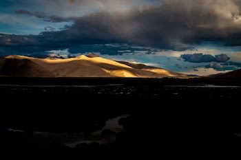 river near mountains under gray clouds