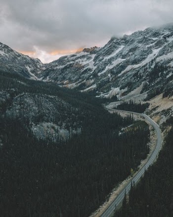 road between mountains under cloudy sky
