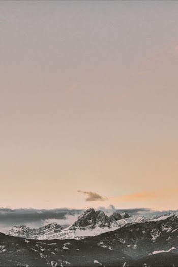rock formation coated with snow under orange sky
