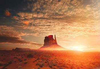 rock formation near hill under white clouds during sunset