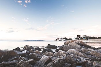 rock formation on seashore under blue sky during daytime