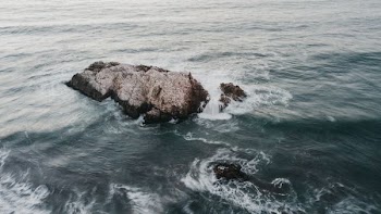 rock formation surrounded with body of water at daytime