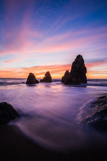 rock formations in body of water at blue hour