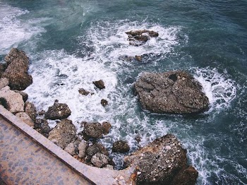 rock formations with crashing seashore at daytime