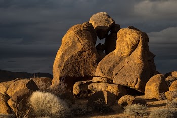 Rock Formed Person Under Heavy Clouds during Daytime