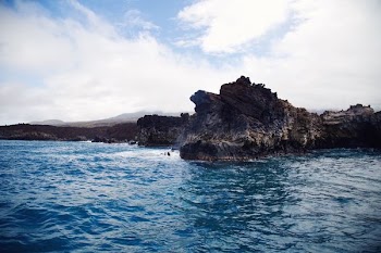 rock in ocean under white sky