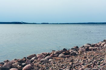 Rock Lot by the Body of Water Under Blue Sky