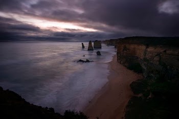 rock mountain near sea under dark sky