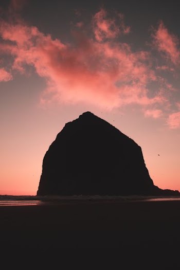 rock mountain surrounded by body of water