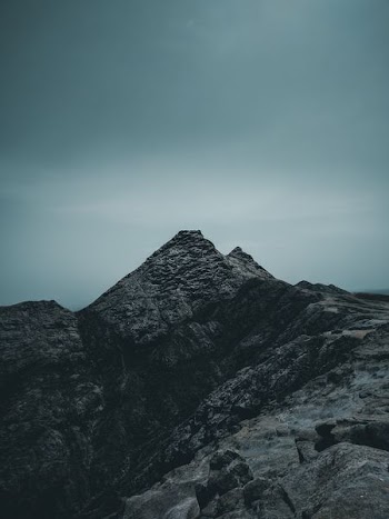 rock mountain under cloudy sky