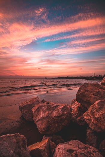 Rocks on Seashore Under Cloudy Sky