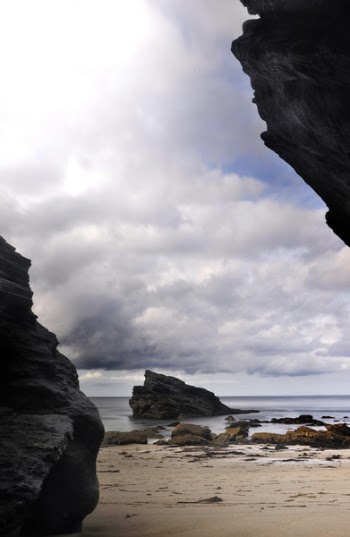 Rocks on Shore Under White Clouds and Blue Sky