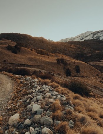 Rocky Road Near Brown and Green Mountains Under Blue Sky · Free Stock Photo