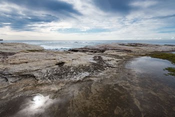 rocky shore under cloudy blue sky