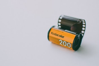 Roll of Kodak Gold Analogue Camera Film on a Light Blue Background