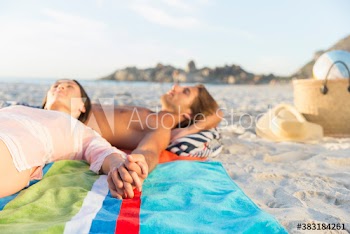 Romantic couple holding hands and relaxing on sunny beach