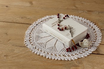 Rosary on Top of Book on Doily Mat