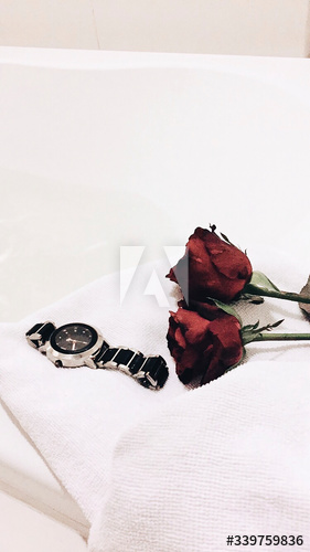 Roses on a bed next to a watch