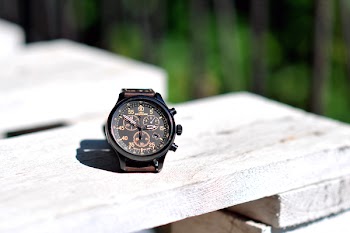 Round Black Chronograph Watch on White Wooden Board