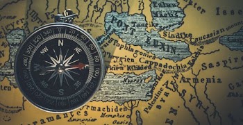 round gray framed compass on brown map