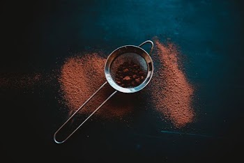 round grey metal filter with brown powder on black surface