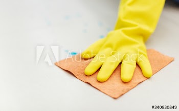 Rubber glove hand drying a wet floor to prevent the contamination