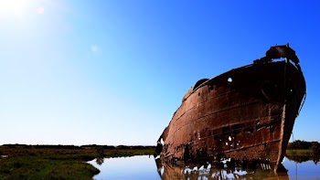 rusted boat near shore under blue sky
