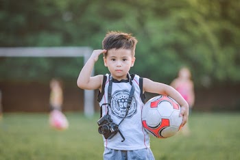 Saluting Boy Wearing White Top Holding Camera