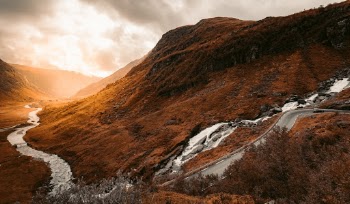 Scenic mountain road trip route through valley at sunset in Norway