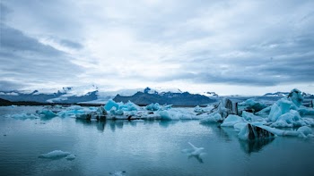 Scenic View Of Snow Capped Mountains Under Cloudy Sky