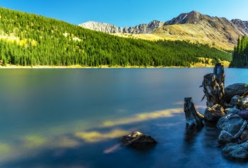 Scenic View Of The Mountains With Green Pine Trees Beside Calm Body of Water