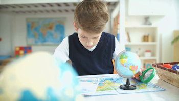 Schoolboy and geographical atlas. The boy student studying ...