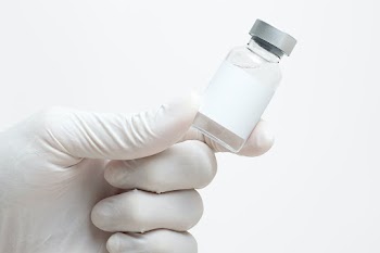 Scientist's hand holding medicine glass vial with blank white label