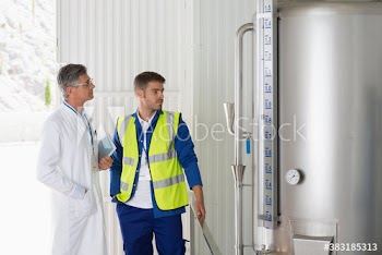 Scientists and worker examining storage tank in factory