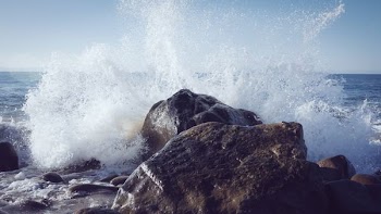 seashore splashed on rock during daytime
