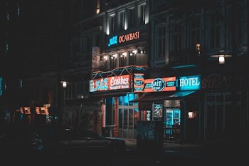sedan parked near building with neon signage turned on at nighttime