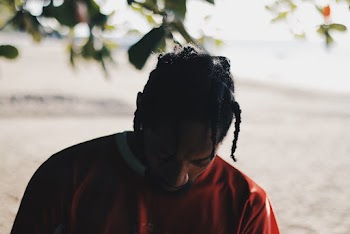 Selective Close-up Photo of Man in Red Sweatshirt Looking Down