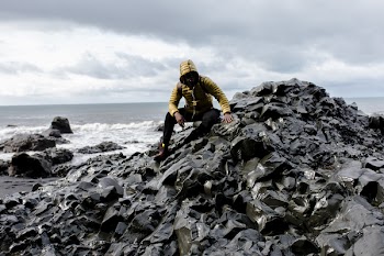Selective Color Photography of Man Wearing Hoodie on Stone Behind Body of Water