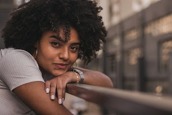 Selective Focus Close-up Photo of Smiling Woman Resting Hand and Head on Metal Railing