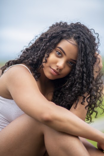 Selective Focus Close-up Photo of Woman in White Top Posing While Sitting