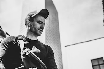 Selective Focus Grayscale Photo of Man Looking Down With Skyscraper in the Background