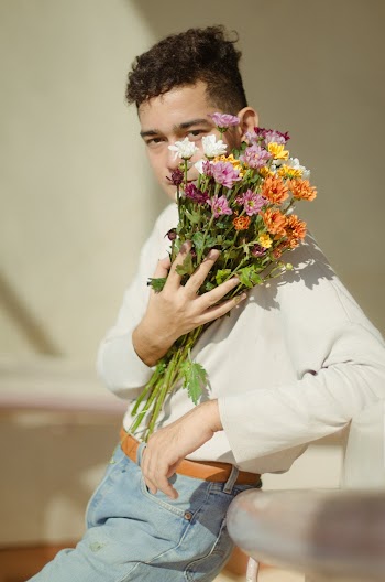Selective-focus of Photography of Man in White Long-sleeved Shirt and Blue Denim Bottoms Holding Bouquet of Flowers