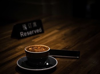 selective focus of teacup filled with coffee on reserved table