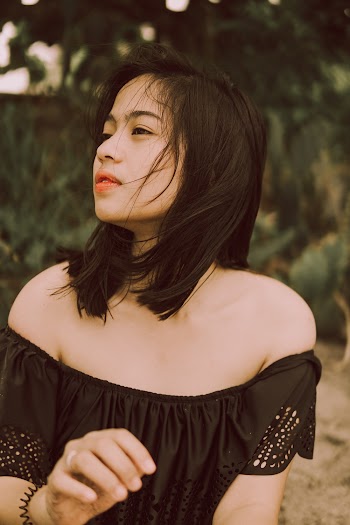 Selective Focus of Woman in Black Off-shoulder Top Posing While Looking Away