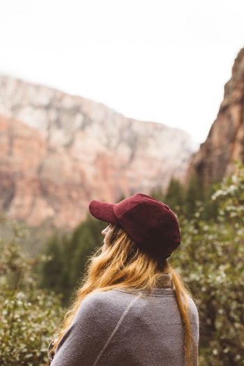 selective focus of woman in gray sweater standing far mountain
