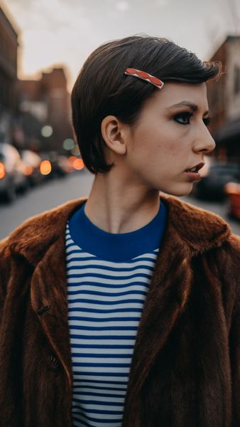 selective focus of woman wearing blue and white stripe top and brown coat