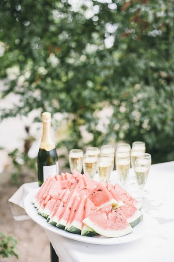 Selective Focus Photo of Bunch of Sliced Watermelons in White Bowl Near Champagne Bottle