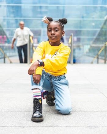 Selective Focus Photo of Girl in Yellow Sweatshirt, Blue Jeans, and Black Leather Boots Posing Alone While Kneeling