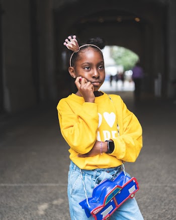 Selective Focus Photo of Girl in Yellow Sweatshirt, Blue Jeans, and, Black Leather Boots Posing While Looking Away